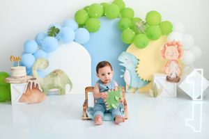 Pastel balloon arch setup with soft blue and green colors featuring a small decorative chair.