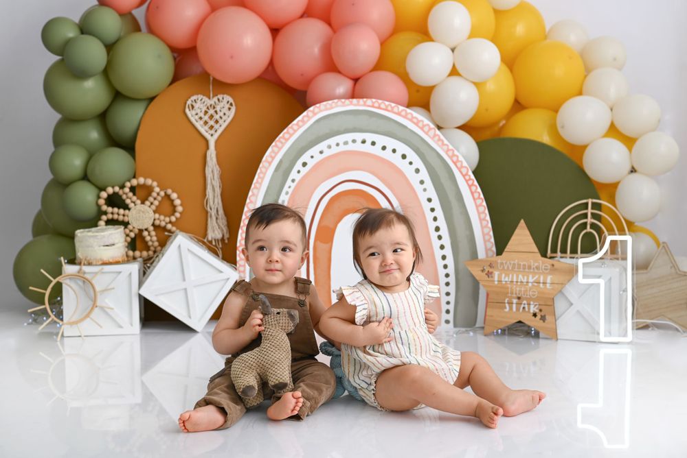 Rainbow balloon arch backdrop with boho decorations and geometric designs for a children's photoshoot.