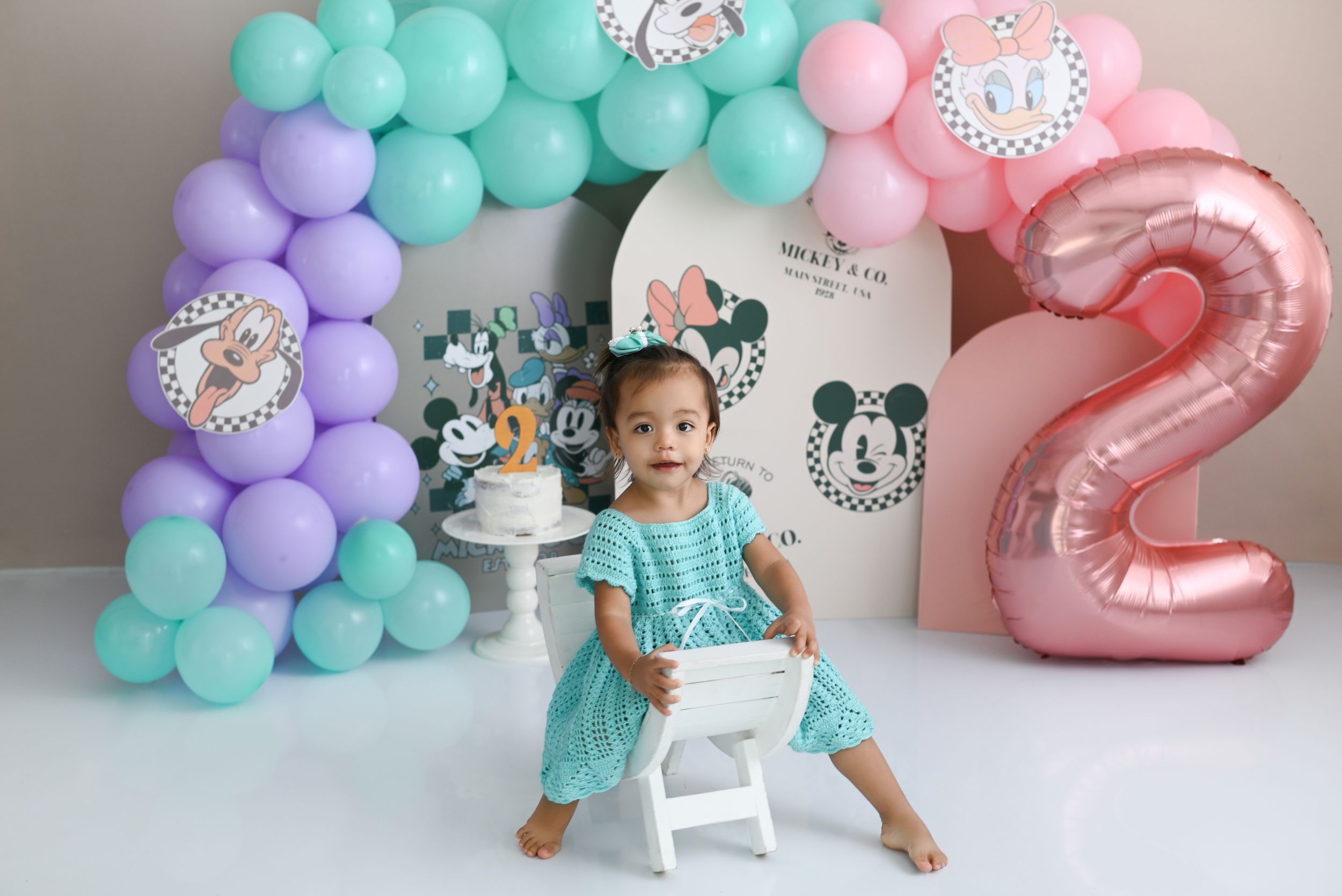 Disney themed birthday setup with pastel balloon arch and number two decoration.