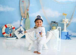 Nautical themed first birthday photoshoot with white and blue decorations.