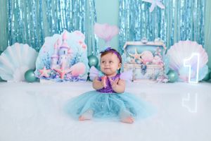 Mermaid themed photo setup with aqua backdrop and seashell decorations.