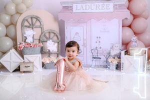 Pink and white themed Laduree-inspired first birthday photo setup with balloon garlands and vintage decor.