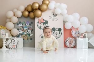 Mickey Mouse themed first birthday party setup with gold and white balloon arch.