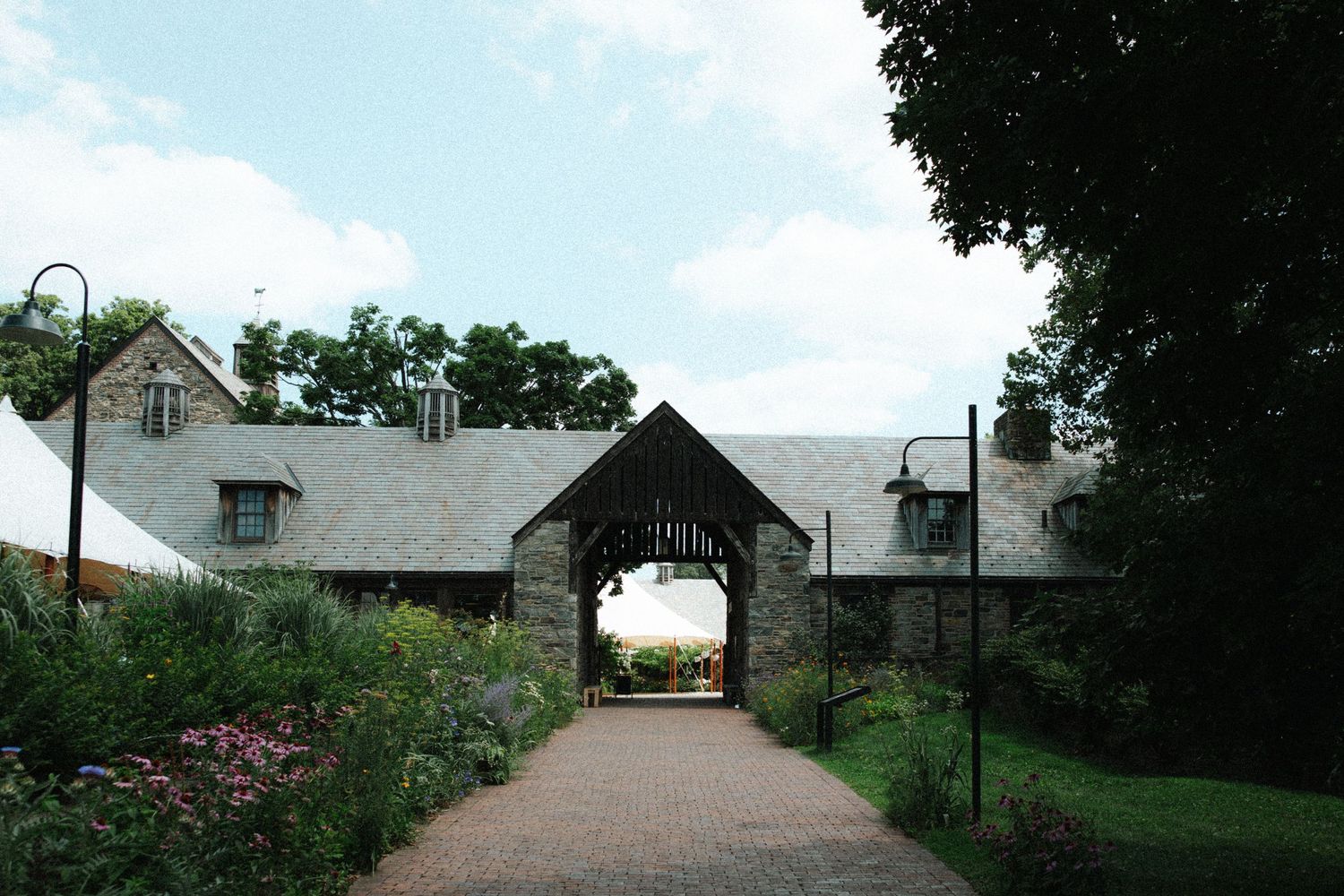 Wedding ceremony setup with white chairs on a lush green lawn facing a historic stone church under cloudy skies.