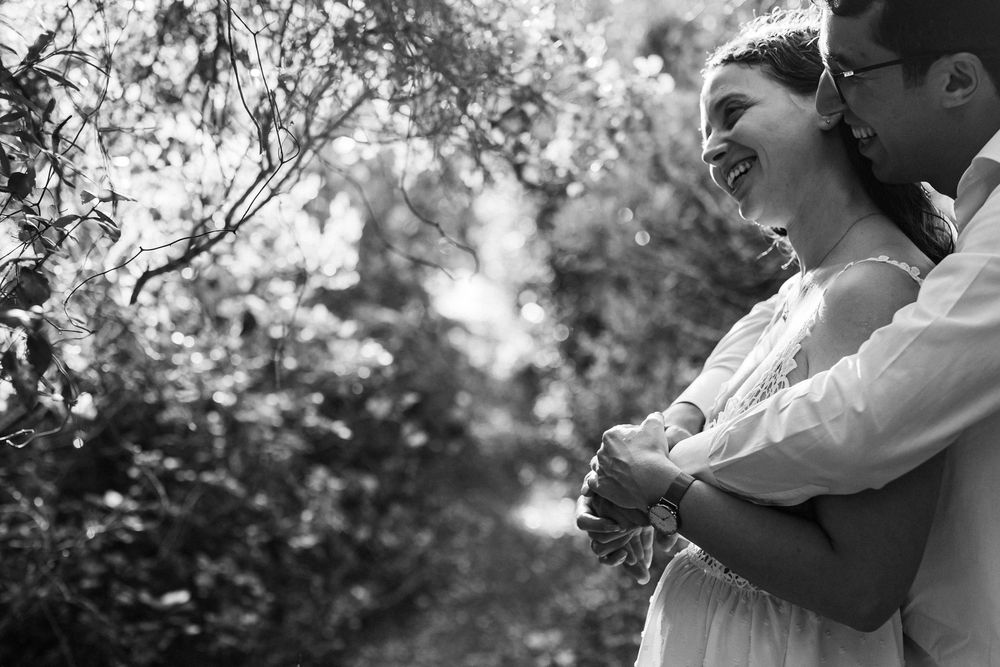 Black and white pre-wedding photo of couple embracing in Arrábida forest with intimate and natural moment