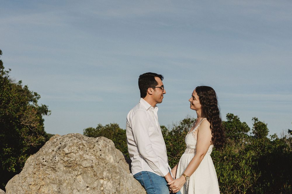 Pre-wedding photos in Serra da Arrábida with couple standing near rocks and wild landscape under warm light