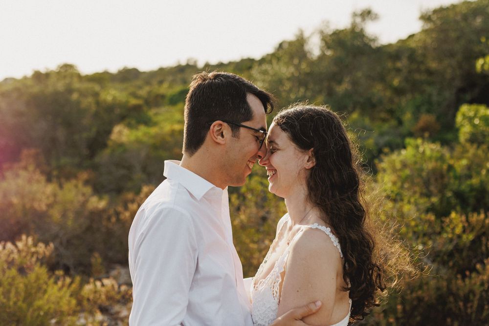 Golden hour pre-wedding photo in Setúbal with couple smiling closely surrounded by nature