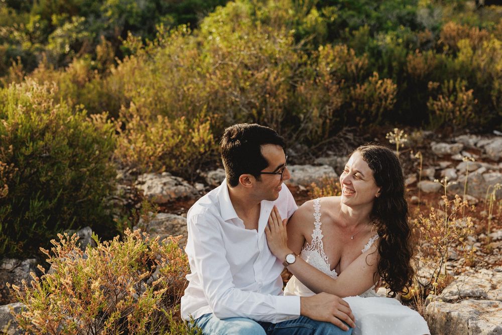 Relaxed pre-wedding photos in Arrábida with couple sitting on the ground laughing in warm sunset light
