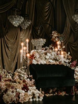 Elegant floral arrangements with white flowers and candles create a romantic ambiance at a wedding reception.