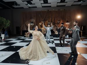 Wedding celebration on black and white checkered dance floor with elaborate floral decor.