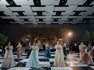 Wedding fashion show on a black and white checkered runway with models in elegant gowns.