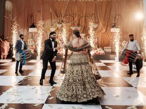 Wedding dance floor with guests celebrating under ornate chandeliers and elegant decor in a luxurious ballroom.