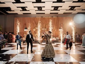 Dramatic wedding reception venue with sparklers and dancing guests on a black and white dance floor.