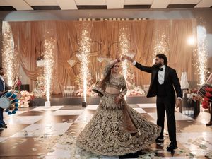 Wedding celebration with sparkler fountains illuminating a dance floor surrounded by elegant white drapery and decor.