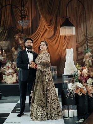 Elegant wedding reception with gold decor, draped fabric backdrop, and floral arrangements.