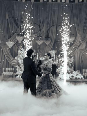 Romantic first dance moment surrounded by theatrical fog and sparkling pyrotechnic effects.