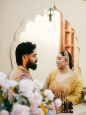 Romantic couple shares an intimate moment in a softly lit room with delicate flowers in foreground.
