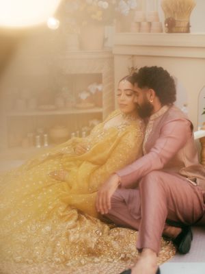 Dreamy portrait of couple relaxing on floor in formal attire with golden dress flowing.