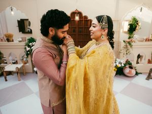 Couple in pink and yellow outfits share tender moments in bright indoor setting.