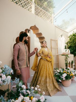 Wedding photoshoot in a bright indoor space decorated with white flowers and a gold lehenga outfit.