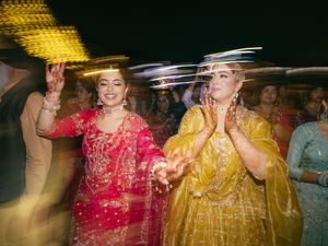 Festive wedding dance celebration with guests in vibrant red and yellow outfits.