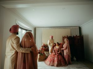 A series of vintage-style dresses in soft pink and cream tones displayed in an elegant room setting.