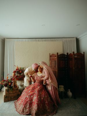 Group in pink traditional attire gathered in a minimalist room with wooden screens.