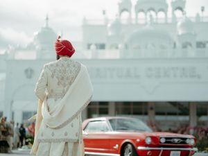 Vintage cars parked outside a white building on a bright sunny day.