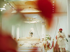 Wedding reception venue with red and gold decorative elements and elegant table settings.