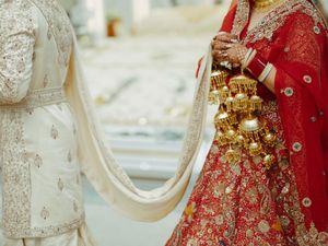 Traditional Indian wedding attire details showing red and gold lehenga with intricate embroidery and white outfit.