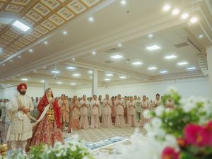 Elegant wedding reception hall with gold geometric ceiling details and floral centerpieces.