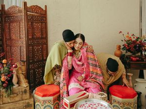 Traditional wedding ceremony with ornate wooden screens and floral decorations in warm lighting.