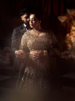 Close-up shot of hands adorned with intricate henna designs and jewelry against a sparkling gold dress.