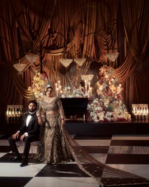 Glamorous wedding photoshoot in a dark venue with dramatic lighting and floral arrangements.
