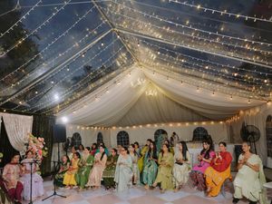 Wedding reception tent decorated with string lights and white fabric draping.