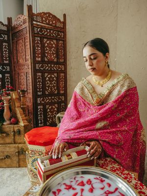 Traditional Indian bride in pink embroidered attire performing pre-wedding rituals.