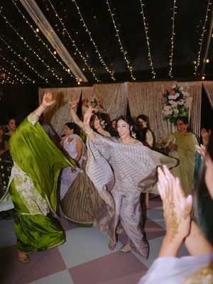 Lively dance celebration under tent with guests in colorful traditional attire.