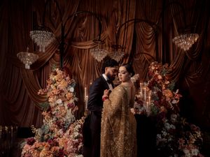 Wedding venue decorated with crystal chandeliers and lush floral arrangements against draped fabric.