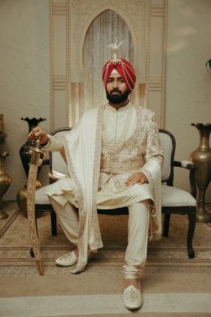 A series of traditional Indian wedding shoes shown in multiple poses against a beige wall and floor.