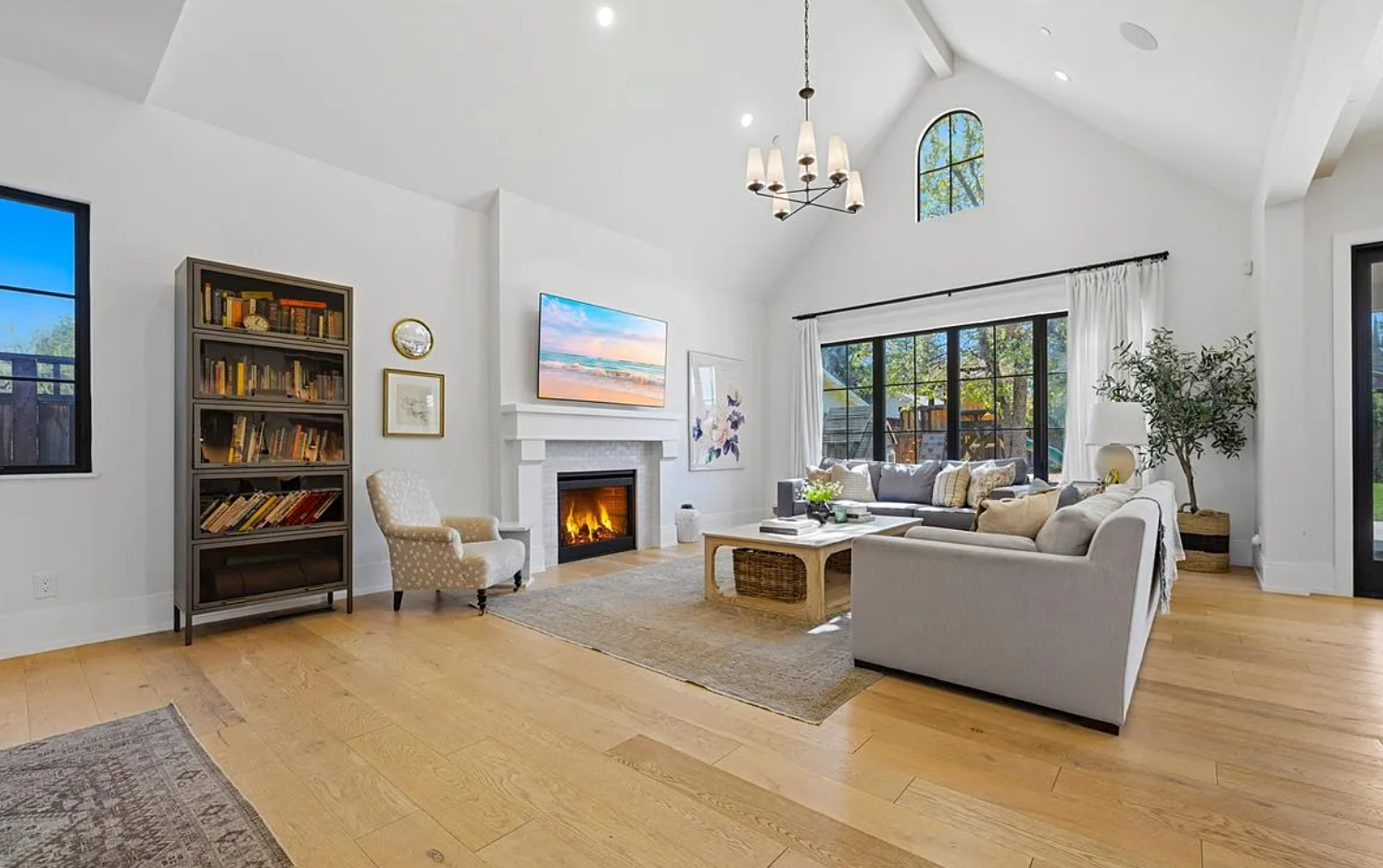 A panoramic view of a modern open-concept living room with white walls, hardwood floors and built-in bookshelves.