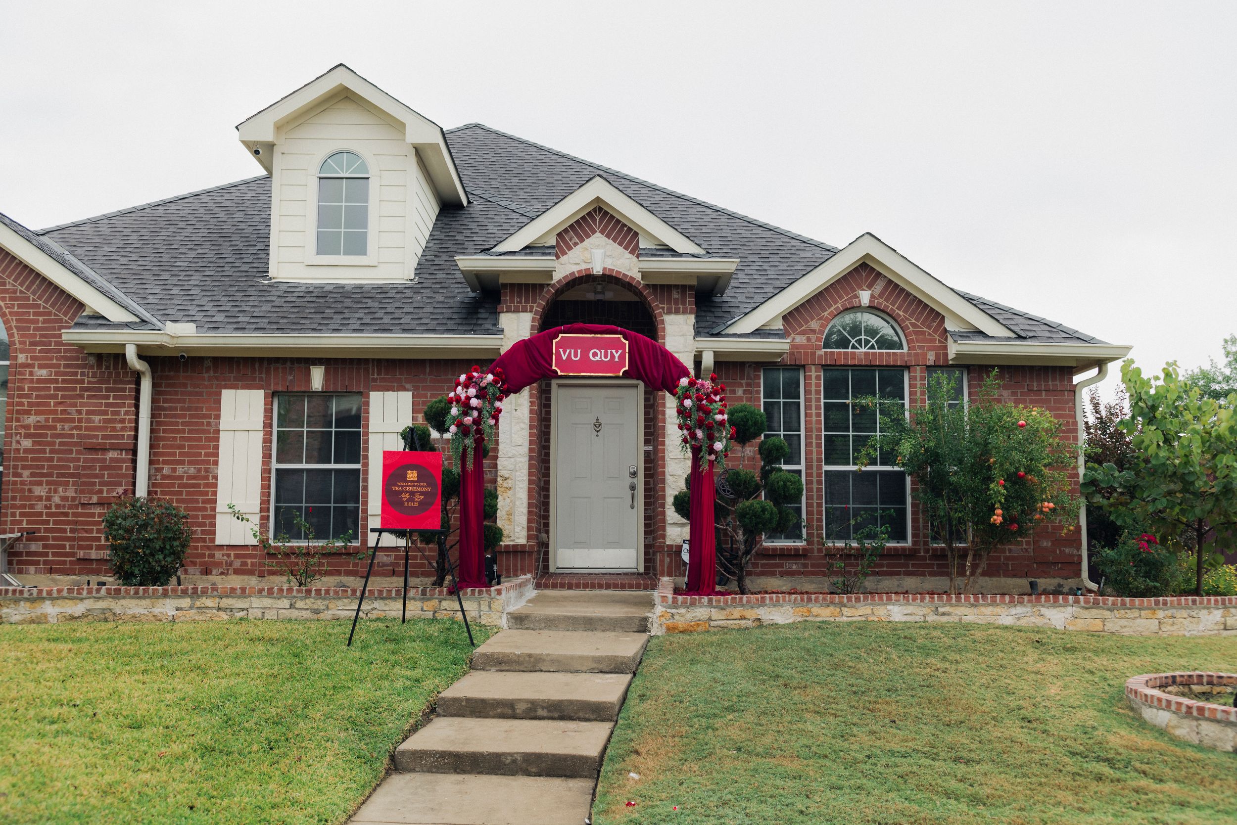 Brick ranch home decorated with red wedding arch and floral arrangements for a traditional Chinese wedding ceremony.