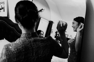 Black and white photo of bride getting hair styled by attendants before wedding ceremony.