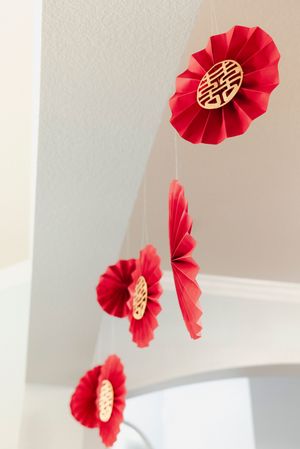 Traditional Chinese red paper fan decorations with double happiness symbols hanging from ceiling.