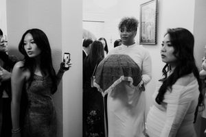 Black and white photo of women in elegant dresses at a Vietnamese wedding ceremony backstage.