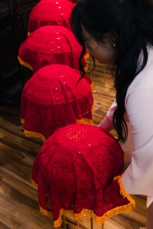 Red lace-covered ceremonial trays with gold fringe at a traditional Vietnamese wedding.