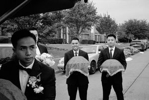 Groomsmen carry lace-covered ceremonial gift trays at a traditional Vietnamese wedding.