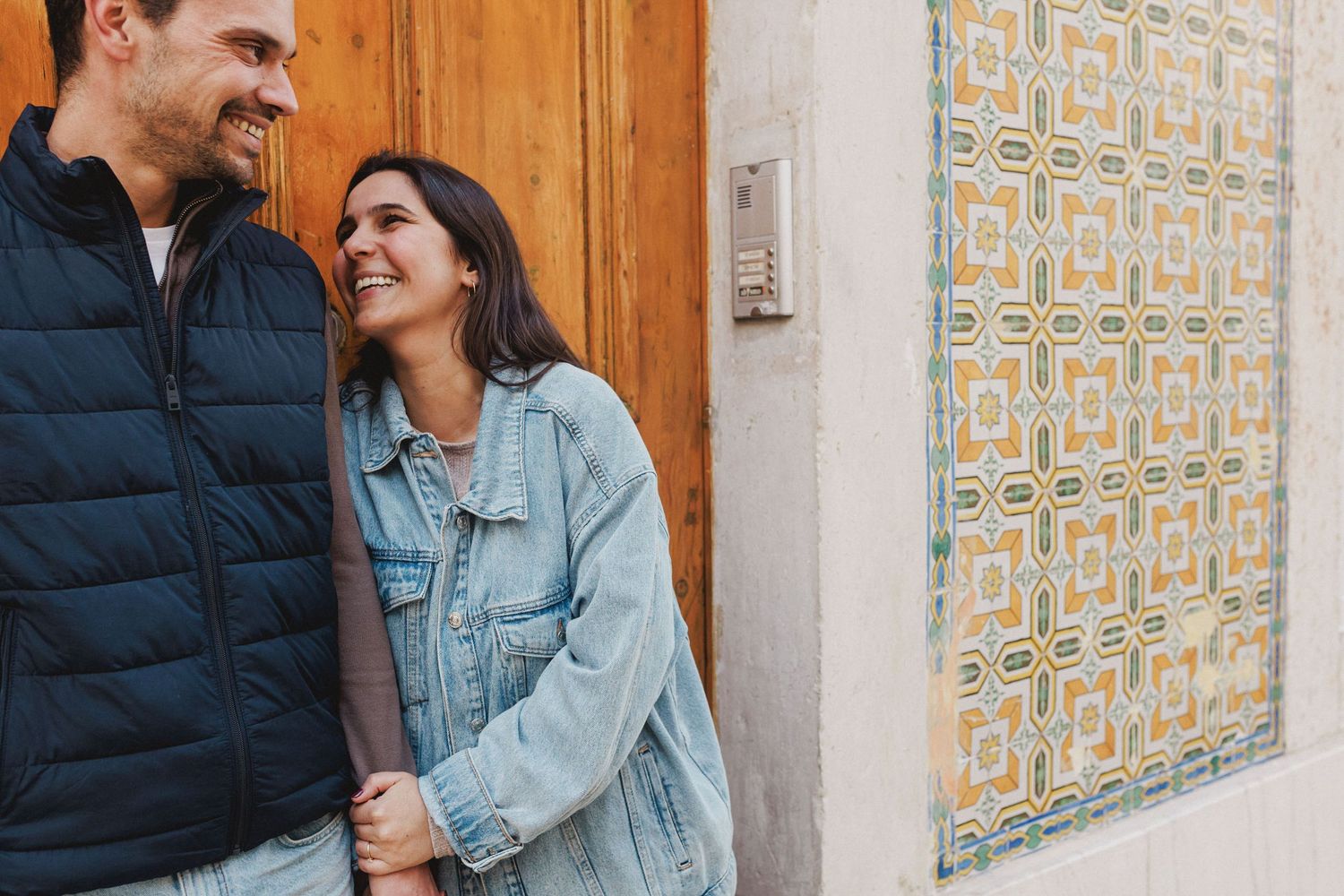 Close-up of happy couple embracing by tiled wall and wooden door in Lisbon city center pre wedding photos