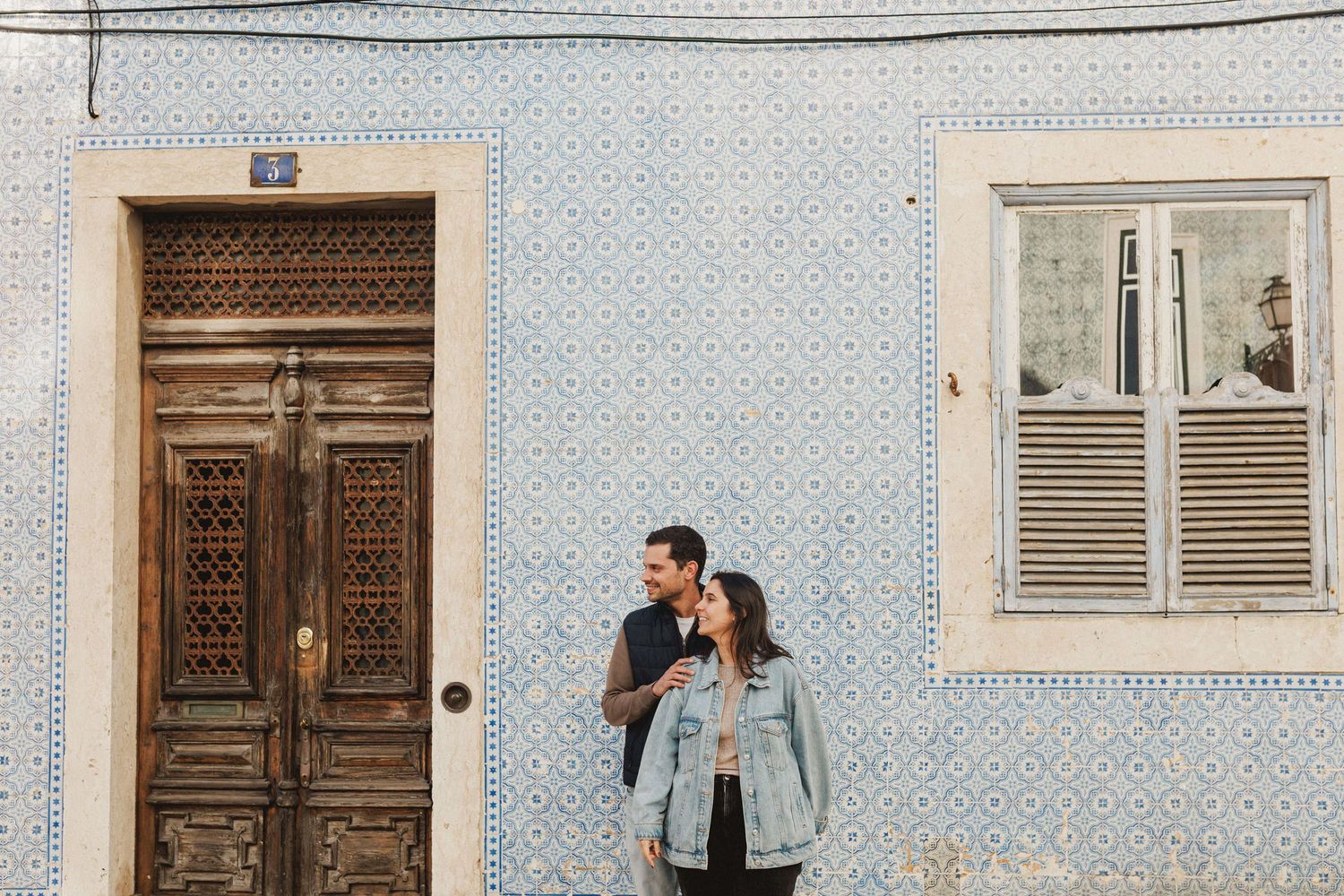 Laughing couple portrait with iconic Lisbon azulejos in background, Baixa engagement photography
