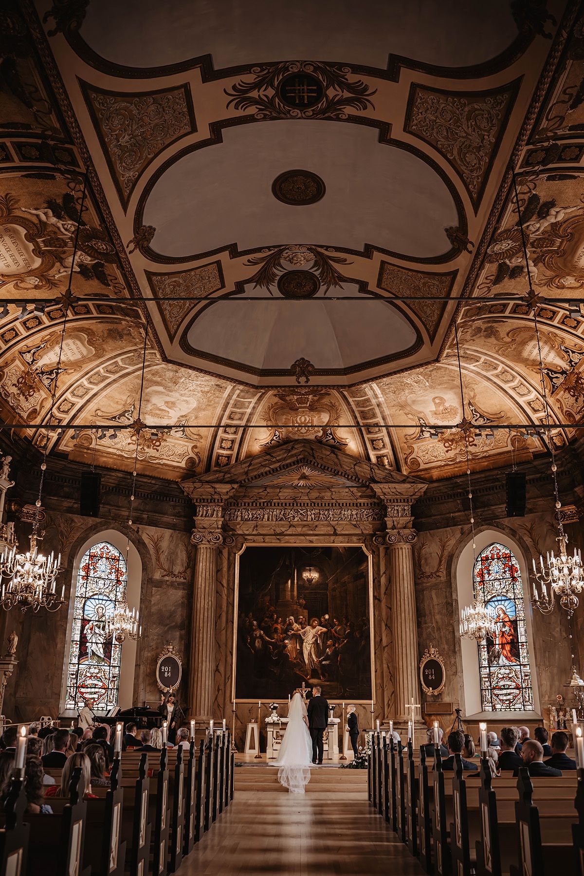 Bröllop i Hedvigs kyrka i Norrköping, vacker takmålning och kyrkogång med brudpar ståendes vid altaret. Bröllopsfotograf Lets Bloom Media.