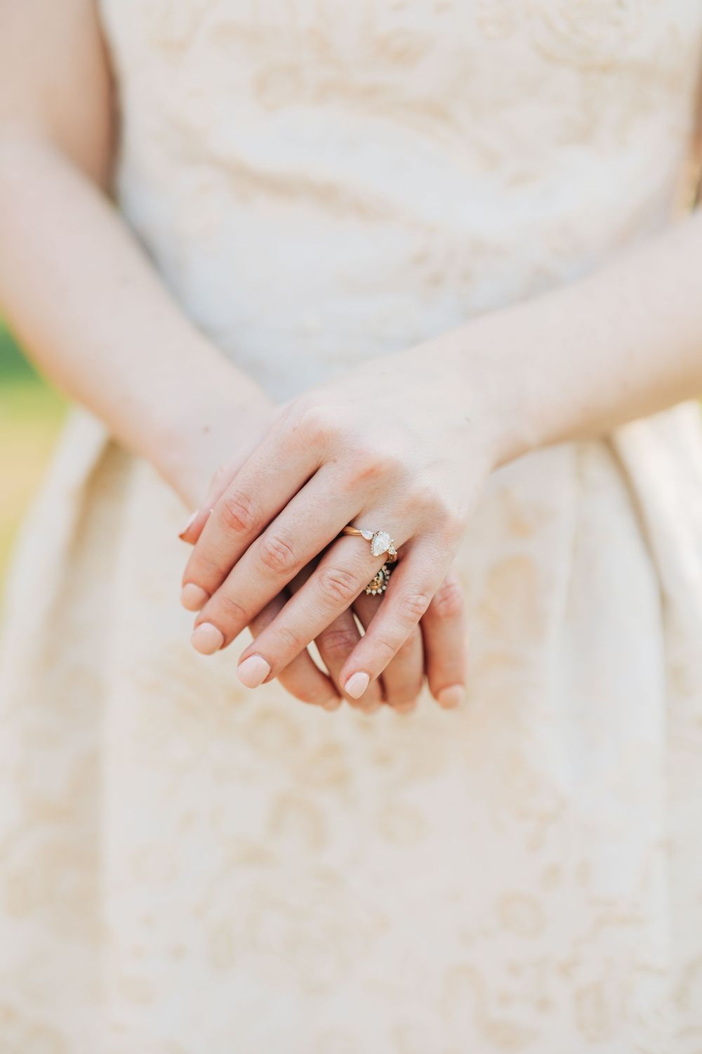 Close-up detail shots of hands wearing an elegant diamond engagement ring with white dress fabric in the background.